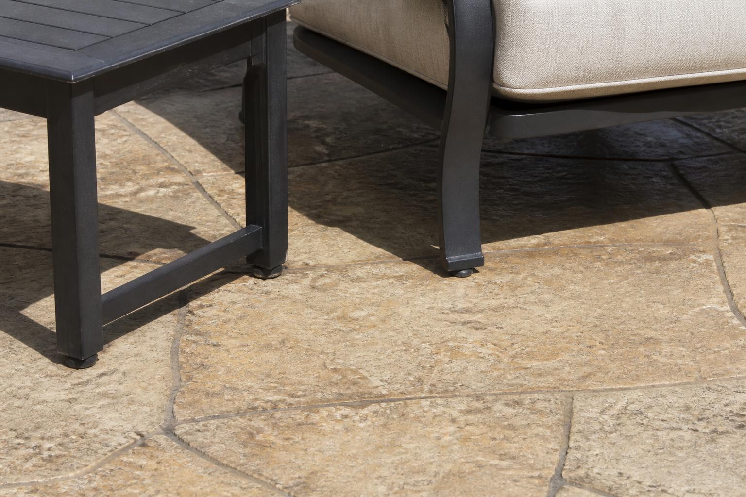 Outdoor chair and end table feet resting on textured stone pavers