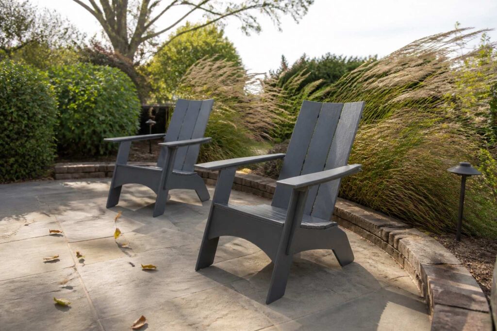 Substantial charcoal Adirondack chairs standing steady on a windy patio